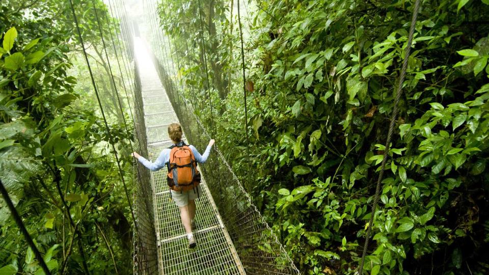 A young woman hikes along a hanging bridge near Arenal Volcano National Park in Costa Rica.