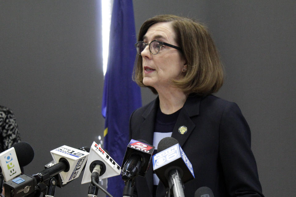 FILE - In this Monday, March 16, 2020 file photo, Gov. Kate Brown speaks at a news conference to announce a four-week ban on eat-in dining at bars and restaurants throughout the state in Portland, Ore., to slow the spread of the new coronavirus. “I am gravely concerned about our ability to deliver basic services over the next six months to a year given the drop in revenues, and that’s why I am encouraging the Legislature to be extremely fiscally prudent,” Brown, a Democrat, said about building the budget for the coming fiscal year. (AP Photo/Gillian Flaccus)