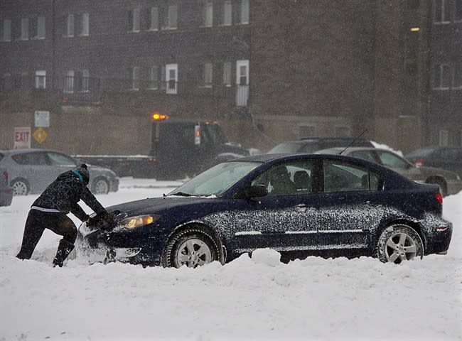 A passenger pushes a car in a parking lot in Halifax on Sunday, Dec.15, 2013. The storm is expected to dump up to 30 centimetres of snow on the region.THE CANADIAN PRESS/Andrew Vaughan