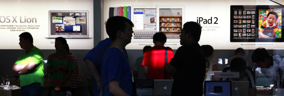 Visitors look at computer products near advertisement for Apple's iPad tablet computer at an Apple store in Beijing, China, Monday, July 2, 2012. Apple agreed to pay $60 million to settle a dispute in China over ownership of the iPad name, a court announced Monday, removing a potential obstacle to sales of the popular tablet computer in the key Chinese market. (AP Photo/Ng Han Guan)