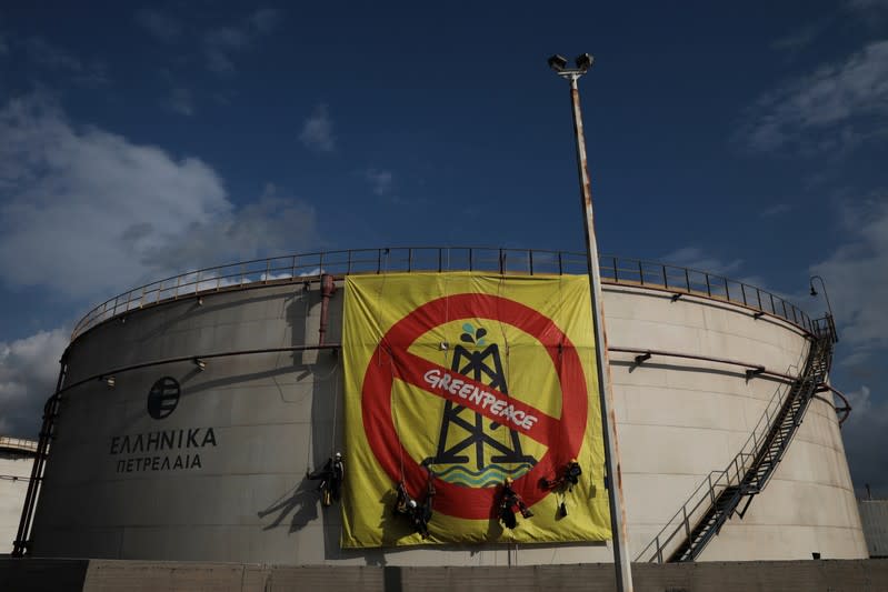 Greenpeace activists hang from an oil tank at the Hellenic Petroleum refineries in Aspropyrgos near Athens