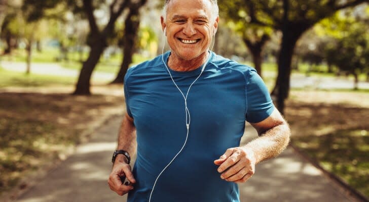 An older man jogs through a park.