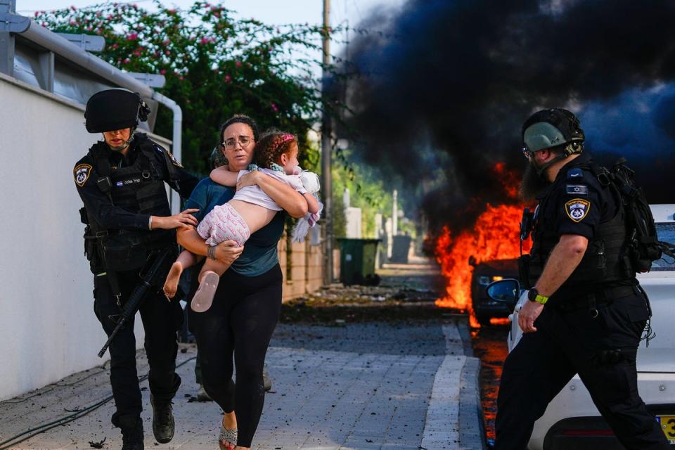 Police officers evacuate a woman and a child from a site hit by a rocket fired from the Gaza Strip (AP)