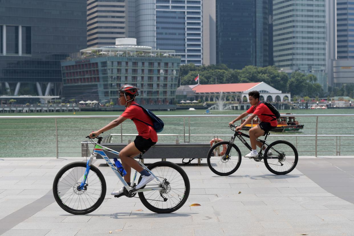 Boys ride their bicycles along the Marina Bay promenade in Singapore on October 10, 2019. (Photo by Roslan RAHMAN / AFP) (Photo by ROSLAN RAHMAN/AFP via Getty Images)