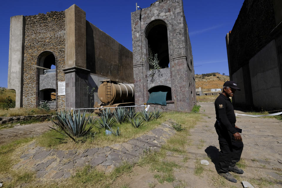 A security guard walks near the entrance of a wastewater treatment company in Ayotlan, Mexico, Thursday, Dec. 9, 2021. The plant was closed at the end of September after an inspection revealed that one of its lagoons holding vinasse, a byproduct of tequila, had a rupture in one of its walls. (AP Photo/Refugio Ruiz)