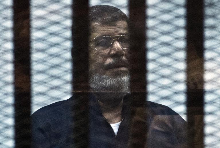 Egypt's ousted president Mohamed Morsi stands behind bars during his trial in Cairo, on June 16, 2015