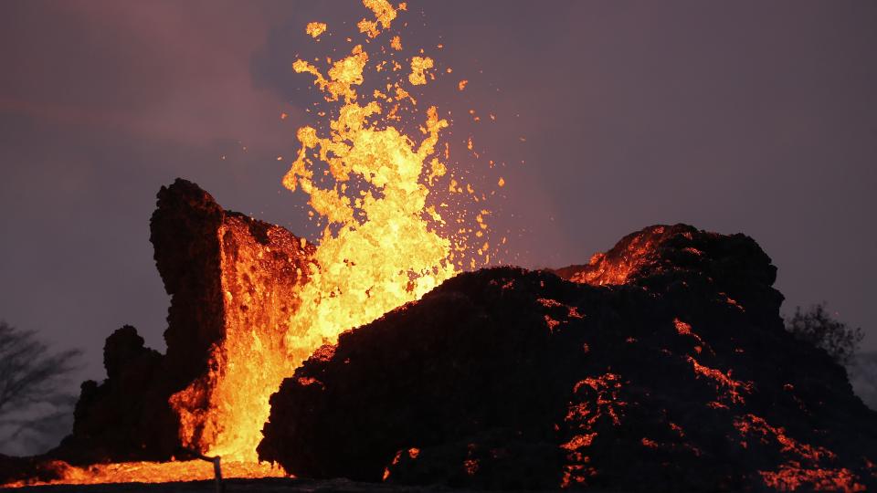 a volcano erupting with bright yellow and red lava flying into the air