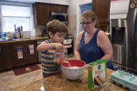 Logan Strauss, 5, adds water to a cake mix while baking with his mother Karen at their home in Basking Ridge, N.J., Wednesday, July 28, 2021. Logan will continue with remote learning from home until he can get the COVID-19 vaccination. (AP Photo/Mark Lennihan)