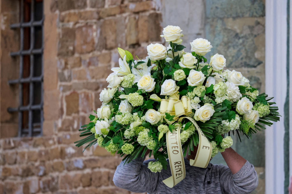 A man carries flowers sent by Matteo Renzi, former Prime Minister of Italy, on the day of the funeral ceremony of Italian designer Roberto Cavalli at the Basilica di San Miniato al Monte, in Florence, Italy, April 15, 2024. REUTERS/Yara Nardi