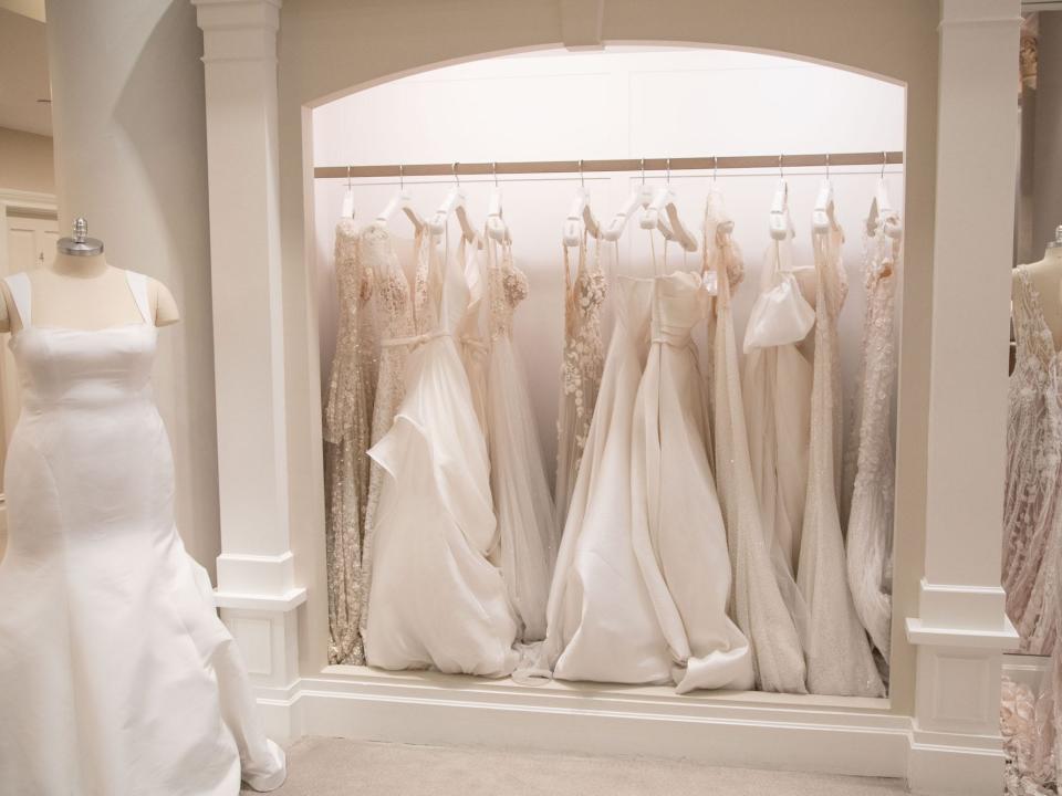 A rack of wedding dresses next to mannequins with wedding dresses on them at Kleinfeld.