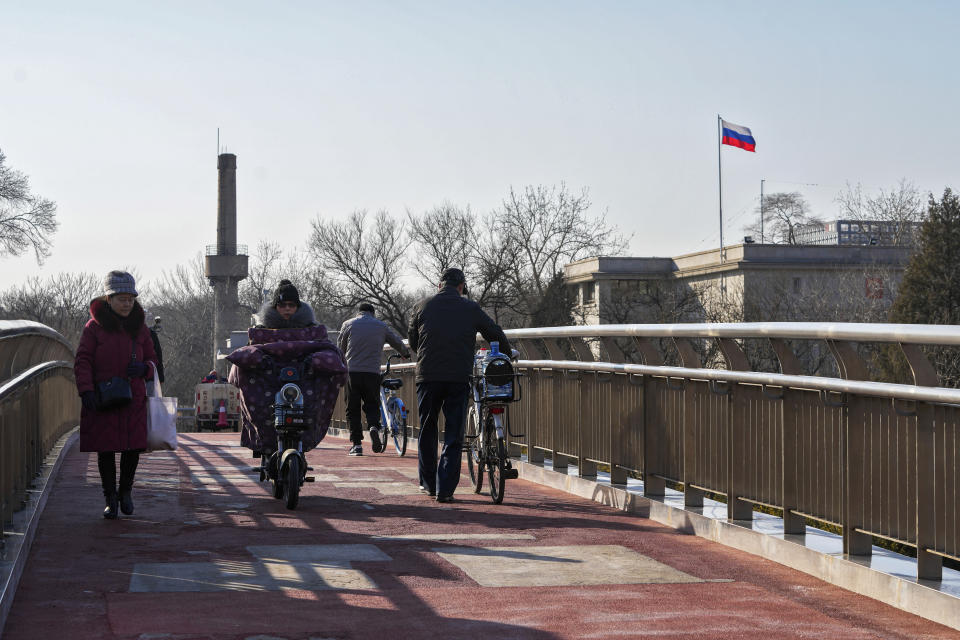 Residents use a pedestrian bridge near the Russian Embassy in Beijing, Thursday, Feb. 24, 2022. China repeated calls for talks to resolve the crisis in Ukraine on Thursday while refusing to criticize Russia's attack and accusing the U.S. and its allies of worsening the situation. (AP Photo/Andy Wong)