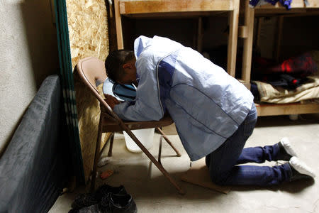 Honduran migrant Ariel, 19, who is waiting for his court hearing for asylum seekers, that have been returned to Mexico to await their legal proceedings under a new policy established by the U.S. government, prays at a shelter in Tijuana, Mexico, March 19, 2019. REUTERS/Jorge Duenes