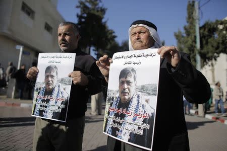 People hold posters of Palestinian minister Ziad Abu Ein at a hospital in the West Bank city of Ramallah December 10, 2014. REUTERS/Ammar Awad