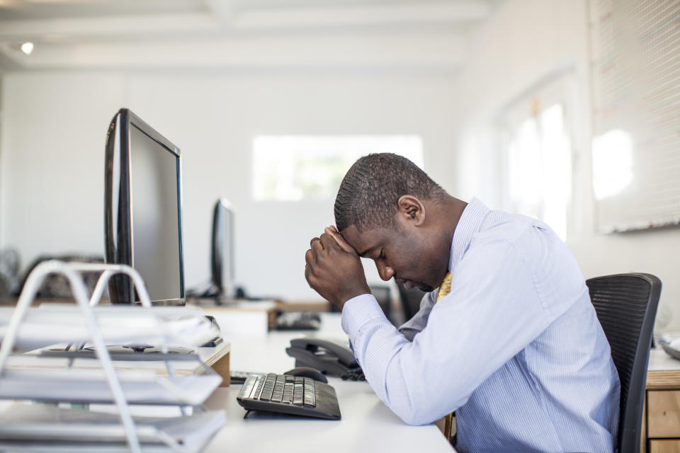 Overworked african businessman sitting at his desk.