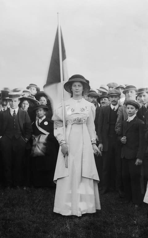 Suffragette Charlotte Marsh in Hyde Park in 1908, wearing a prisoner's medal and carrying the purple, white and green tricolour flag. - Credit: Museum of London