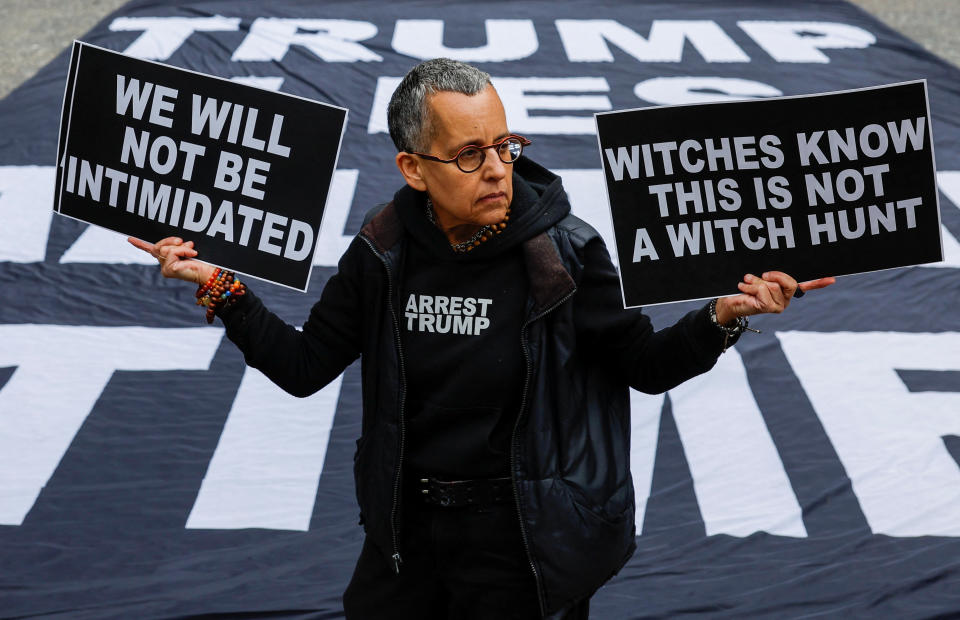 An anti-Trump protester holds a sign saying Witches Know This Is Not a Witch Hunt, outside the courthouse on Tuesday. 