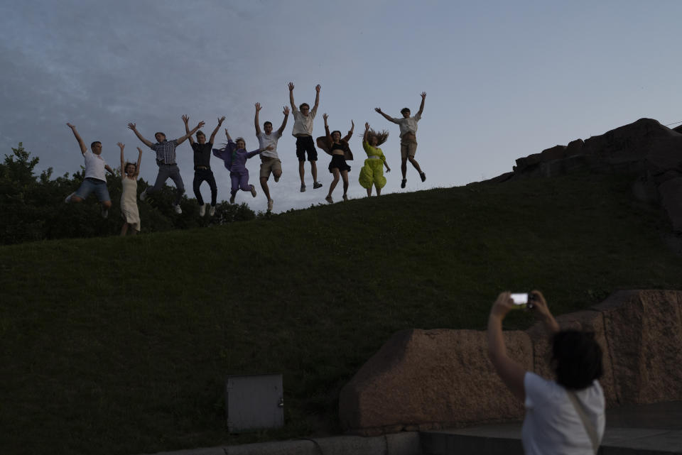 A group of recent high school grads leap as they pose for photos to celebrate their graduation in Kyiv, Ukraine, Monday, July 3, 2023. (AP Photo/Jae C. Hong)