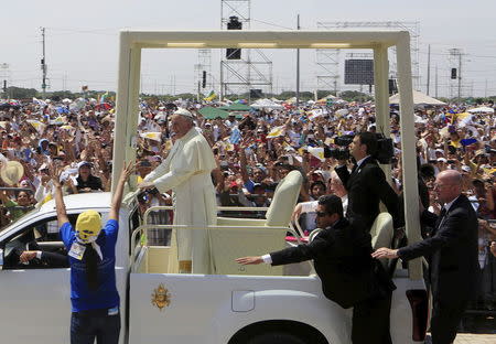 Pope Francis drives past the faithfuls as security reaches out to stop a woman trying to approach the Popemobile during his arrival at Parque Samanes where he will celebrate mass in Guayaquil, Ecuador, July 6, 2015. REUTERS/Jose Miguel Gomez