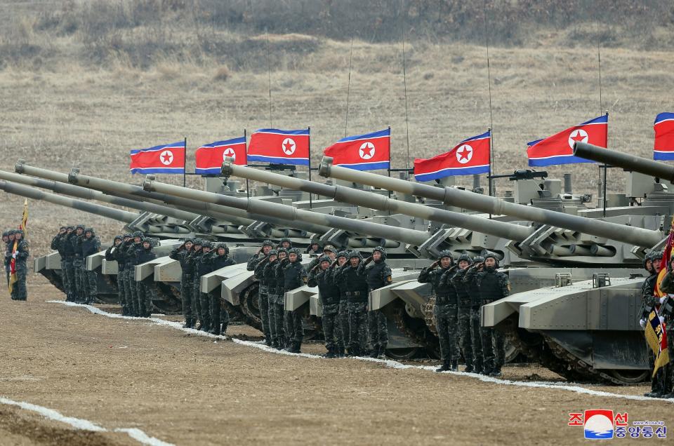 Military members salute during a military demonstration involving tank units in North Korea.