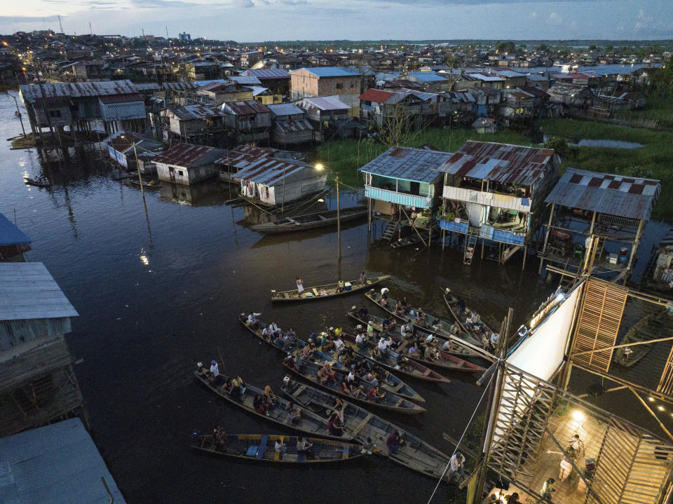 Spectators sit on boats watching a film projected on a screen set up on a wooden structure during the Muyuna Floating Film Festival, that celebrares tropical forests, in the Belen neighborhood of Iquitos, Peru, Saturday, May 25, 2024. (AP Photo/Rodrigo Abd)