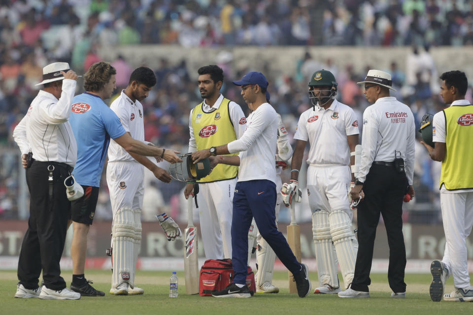 Bangladesh's Nayeem Hasan, third left, stands as physiotherapists of India and Bangladesh look into the helmet after he was injured by a delivery by India's Mohammed Shami during the first day of the second test match between India and Bangladesh, in Kolkata, India, Friday, Nov. 22, 2019. (AP Photo/Bikas Das)