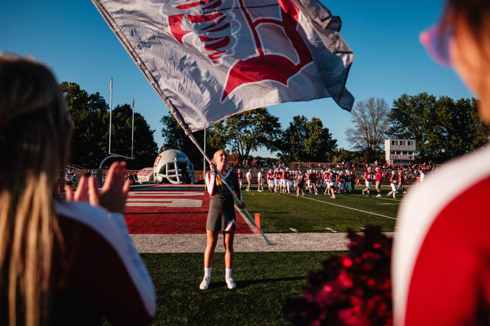 Dover cheerleader Caycee Albaugh, a junior, waves the Dover flag during pregame warmups in week 5 high school football action against Steubenville, Friday, Sept. 15 at Crater Stadium in Dover.
