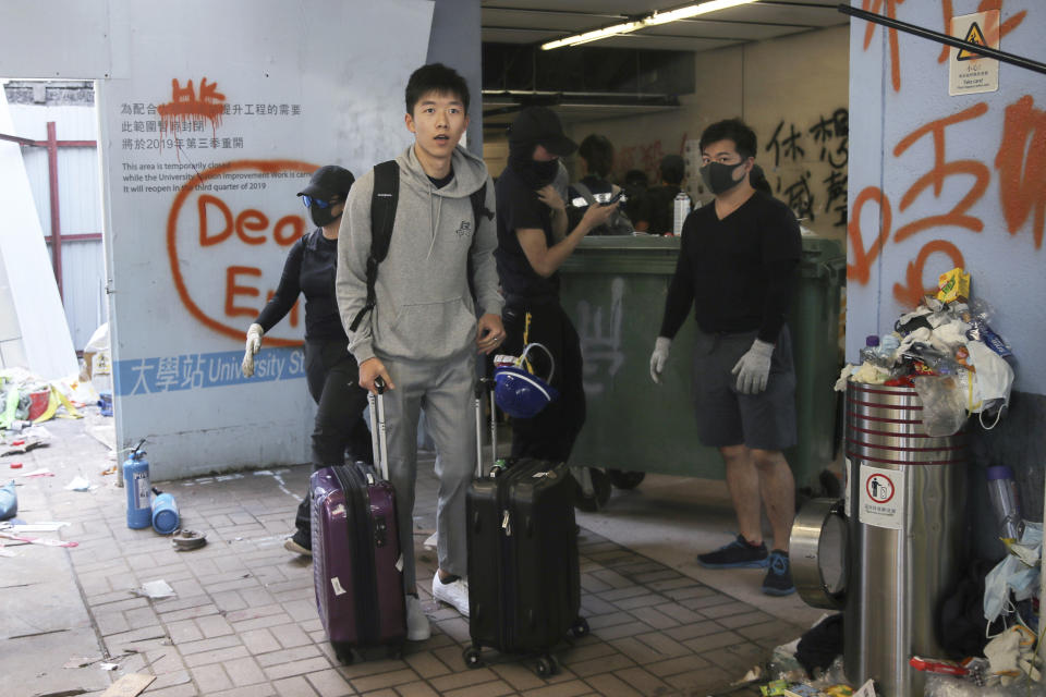 A student pushes his luggage past pro-democracy protesters as he leaves the Chinese University of Hong Kong following a clash in Hong Kong, Wednesday, Nov. 13, 2019. University students from mainland China are fleeing Hong Kong, and classes for primary and secondary school students have been suspended as attacks and clashes turn increasingly violent in the city's five-month long anti-government unrest. (AP Photo/Kin Cheung)