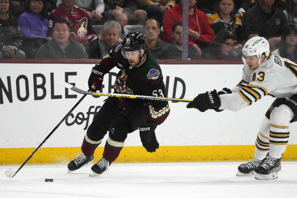 Arizona Coyotes left wing Michael Carcone (53) skates with the puck against Boston Bruins left wing Danton Heinen (43) during the first period of an NHL hockey game Tuesday, Jan. 9, 2024, in Tempe, Ariz. (AP Photo/Ross D. Franklin)