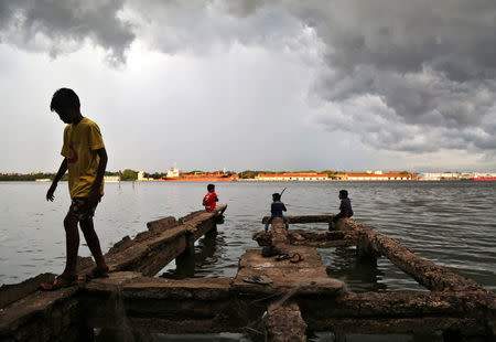 A boy walks through a damaged jetty as pre-monsoon clouds gather above the Vembanad Lake in Kochi, India, May 11, 2018. REUTERS/Sivaram V