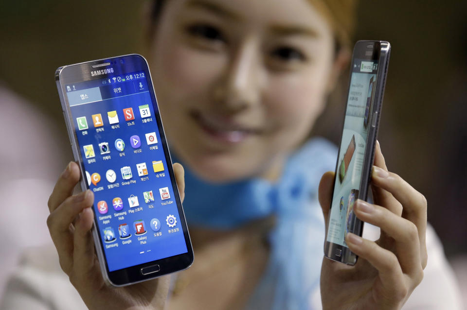 FILE - In this Oct. 10, 2013 file photo, a model poses with Samsung Electronics' smartphones the Galaxy Round, at Korea Electronics Show in Goyang, west of Seoul, South Korea. Samsung Electronics Co., which is preparing for the global launch of the Galaxy S5 smartphone on April 11, 2014, said it is making “concentrated efforts” to ensure its communications around the world respectfully portray women. Some of its promotions and corporate events in the past year were criticized as sexist and demeaning. The advertising of LG Electronics Inc. has also been under scrutiny in South Korea and abroad for its portrayal of women. (AP Photo/Lee Jin-man, File)
