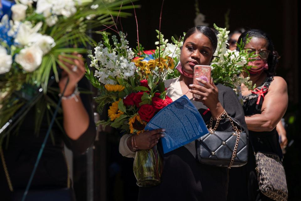 Women carry floral arrangements after a funeral service for Detroit Police Officer Loren Michael Courts, a five-year veteran of the 2nd Precinct Special Operations Cease Fire Unit, at Greater Grace Temple in Detroit on Monday July 18, 2022. Courts was was shot and killed after being ambushed by a gunman in Detroit's west side on July 6, 2022. 