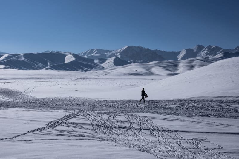 An Afghan labourer on his way to work backdropped by snow covered mountains in Afghanistan's Bamyan Province.  Afghanistan has experienced heavy rainfall and cold weather over the past three weeks, resulting in at least 60 deaths and 23 injuries. Oliver Weiken/dpa