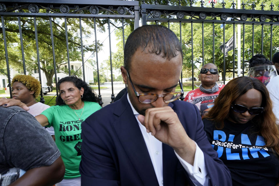 Mona Hardin, background left in green, mother of Ronald Greene, prays outside the gates of the governor's mansion in Baton Rouge, La., May 27, 2021, protesting the death of Greene, who died in the custody of Louisiana State Police in 2019. Foreground is Ron Haley, attorney for the Greene family. (AP Photo/Gerald Herbert)
