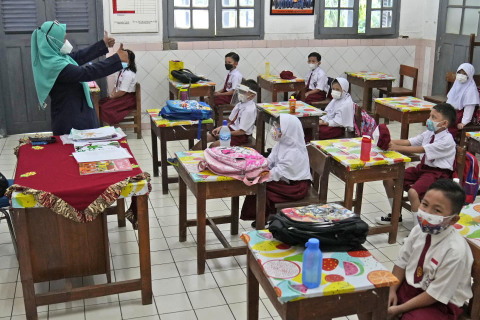 Students wearing face masks to help prevent the spread of COVID-19 attend a class during the first day of school reopening at an elementary school in Jakarta, Indonesia, Monday, Aug. 30, 2021. Authorities in Indonesia's capital kicked off the school reopening after over a year of remote learning on Monday as the daily count of new COVID-19 cases in the country continues to decline. (AP Photo/Dita Alangkara)