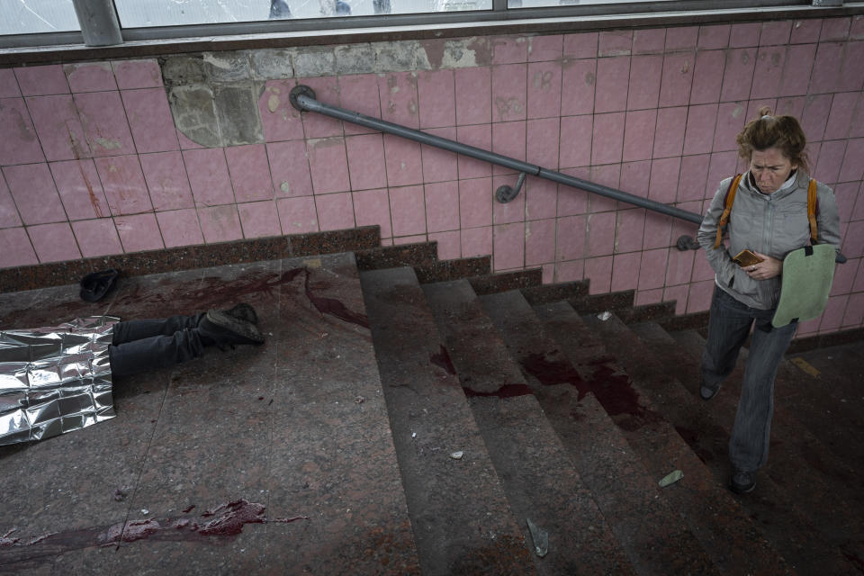 A woman walks next to the body of a man killed during shelling in Kharkiv, eastern Ukraine, Thursday, May 26, 2022. (AP Photo/Bernat Armangue)