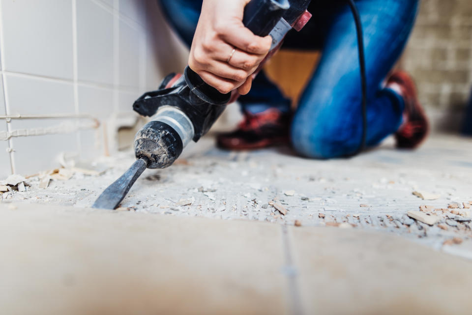 Woman removing old tiles, renovating the bathroom.