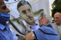 The father of Ibrahim Harb, 35, center, a Lebanese man who was critically injured in the massive explosion at Beirut's port last year and who died on Monday nearly 14 months after the blast, mourns on his son's portrait during his funeral procession, in Beirut, Lebanon, Tuesday, Sept. 28, 2021. On Aug. 4, 2020, hundreds of tons of ammonium nitrate, a highly explosive material used in fertilizers, ignited after a massive fire at the port. The death brings to at least 215 the number of people who have been killed by the blast, according to official records. (AP Photo/Hussein Malla)