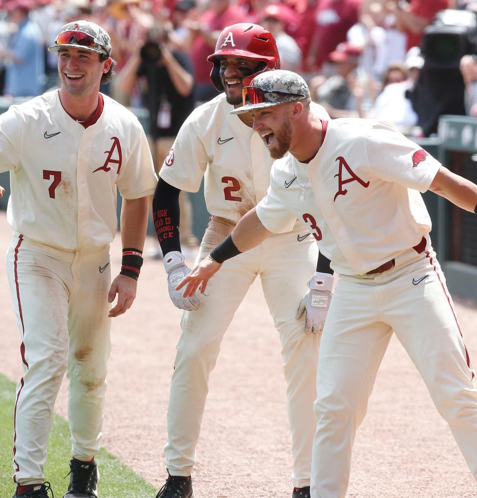University of Arkansas-Fayetteville baseball players (from left) Cayden Wallace (7), Jalen Battles (2), and Zack Gregory (3) wait for Michael Turner to cross home plate after Turner hit a two-run home run during the Razorbacks' SEC conference game against Ole Miss on May 1, 2022, at Baum-Walker Stadium in Fayetteville, Ark.