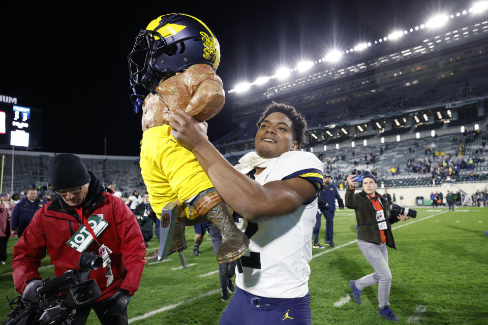 Michigan's Will Johnson, center, carries the Paul Bunyan trophy after defeating Michigan State in an NCAA college football game, Saturday, Oct. 21, 2023, in East Lansing, Mich. (AP Photo/Al Goldis)