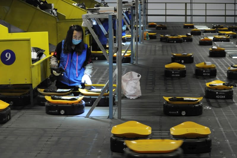 Employees sort parcels with AGVs at a logistic centre of a postal service a day ahead of the Singles' Day online shopping festival in Nanjing