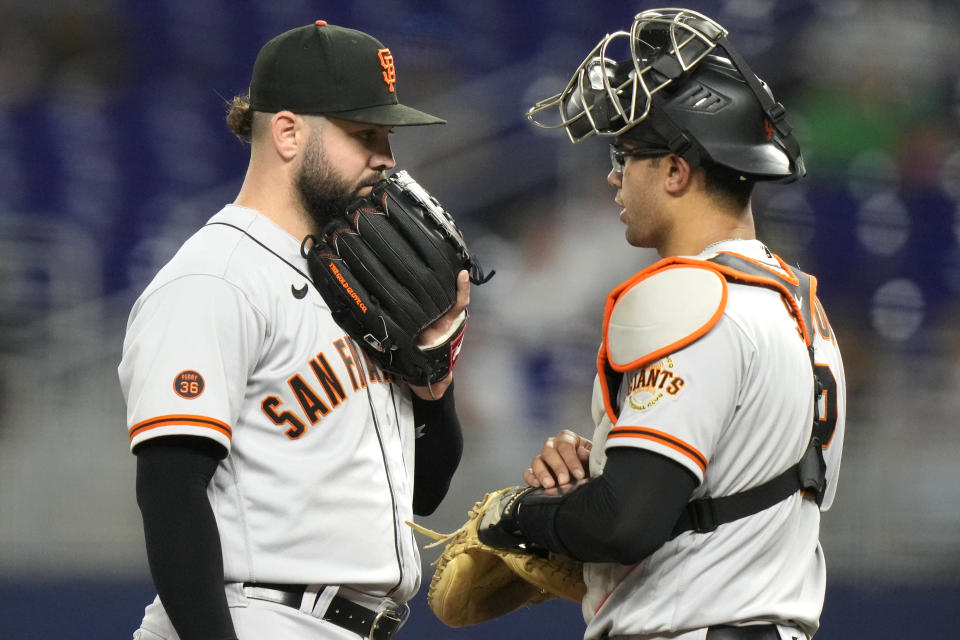 San Francisco Giants pitcher Jakob Junis, left, talks with San Francisco Giants catcher Blake Sabol during the fourth inning of a baseball game against the Miami Marlins, Tuesday, April 18, 2023, in Miami. (AP Photo/Lynne Sladky)