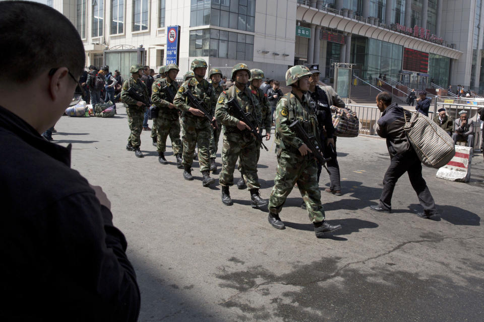 Heavily armed Chinese paramilitary police men march past the site of the Wednesday explosion outside the Urumqi South Railway Station in Urumqi in northwest China's Xinjiang Uygur Autonomous Region on Thursday, May 1, 2014. Recent deadly attacks in China blamed on Islamic extremists are getting bolder and bloodier, targeting civilians rather than the authorities and further challenging Beijing’s ability to stop them. (AP Photo/Ng Han Guan)