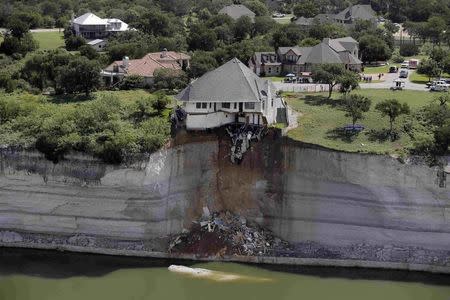 Crews prepare to set a house on fire, days after part of the ground it was resting on collapsed into Lake Whitney, Texas June 13, 2014. REUTERS/Brandon Wade