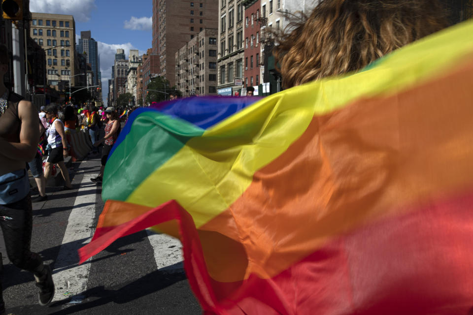 FILE - In this June 30, 2019, file photo parade-goers carrying rainbow flags walk down a street during the LBGTQ Pride march in New York, to celebrate five decades of LGBTQ pride, marking the 50th anniversary of the police raid that sparked the modern-day gay rights movement. Democrats flooded Twitter and email inboxes this week with praise for the watershed Supreme Court decision shielding gay, lesbian and transgender people from job discrimination. (AP Photo/Wong Maye-E, File)