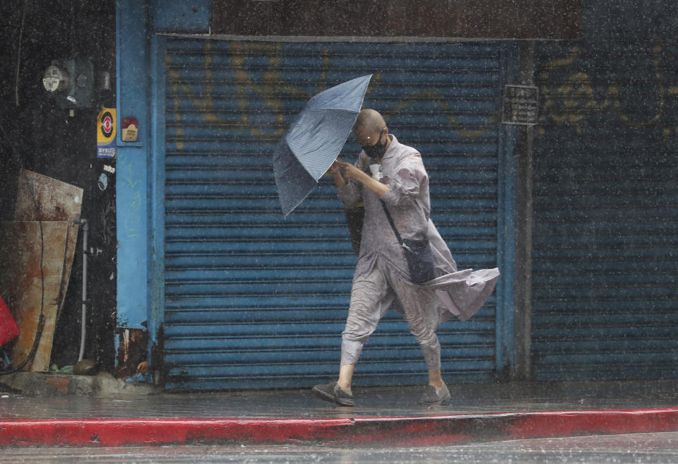 A Buddhist nun struggles with her umbrella against gusts of wind generated by Typhoon Gaemi in Taipei, Taiwan, Wednesday, July 24, 2024. (AP Photo/Chiang Ying-ying)