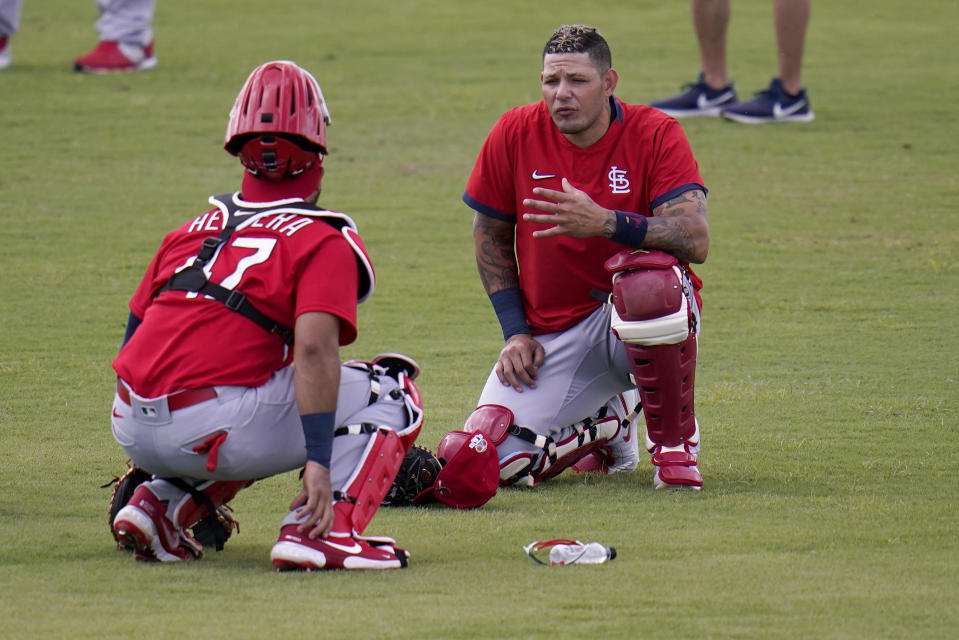 El receptor de los Cardenales de San Luis Yadier Molina (derecha) charla con el también receptor Iván Herrera durante un entrenamiento en Jupiter, Florida, el lunes 22 de febrero de 2021. (AP Foto/Jeff Roberson)