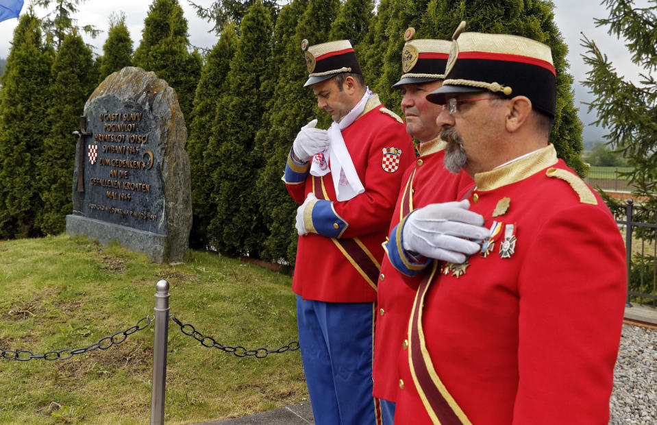 Honor guards stand next to a monument during a liturgical service for victims of the end of WWII events in Bleiburg, southern Austria, Saturday, May 18, 2019. Thousands of Croatian far-right supporters have gathered in a field in southern Austria to commemorate the massacre of pro-Nazi Croats by communists at the end of World War II. (AP Photo/Darko Bandic)