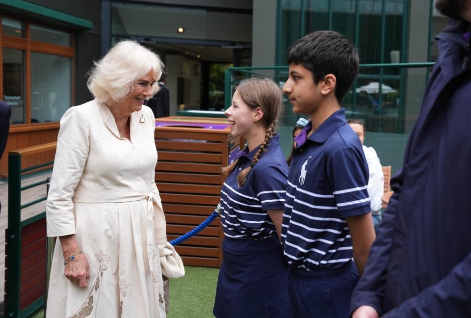 ​LONDON, ENGLAND - JULY 10: Queen Camilla meets ball kids Natalia from Burntwood School in Wandsworth and Yug from Harris Academy Wimbledon during a visit to the All England Lawn Tennis and Croquet Club in Wimbledon, south west London, on day ten of the Wimbledon Tennis Championships on July 10, 2024 in London, England. (Photo by Jordan Pettitt - WPA Pool/Getty Images)