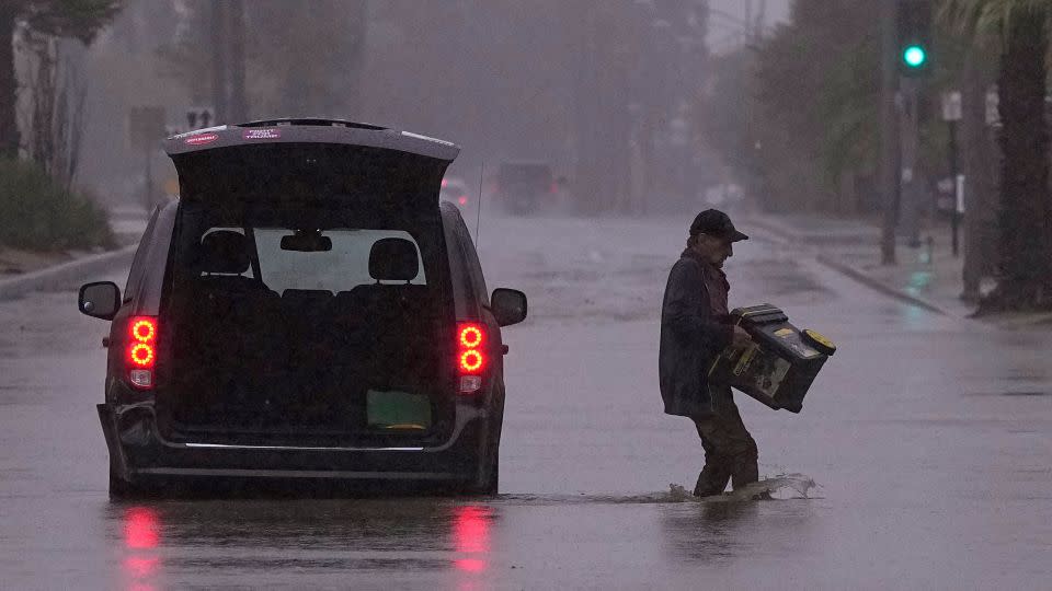 A motorist removes belongings from his vehicle after becoming stuck in a flooded street in Palm Desert, California, on Sunday, August 20.  - Mark J. Terrill/AP