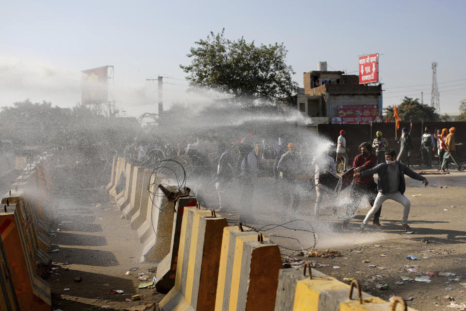 Police use water cannon to disperse protesting farmers, as they attempt to move towards Delhi, at the border between Delhi and Haryana state, Friday, Nov. 27, 2020. Thousands of agitating farmers in India faced tear gas and baton charge from police on Friday after they resumed their march to the capital against new farming laws that they fear will give more power to corporations and reduce their earnings. While trying to march towards New Delhi, the farmers, using their tractors, cleared concrete blockades, walls of shipping containers and horizontally parked trucks after police had set them up as barricades and dug trenches on highways to block roads leading to the capital. (AP Photo/Altaf Qadri)